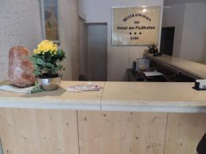a counter with a vase of flowers on top of it at Hotel Am Flughafen in Cologne