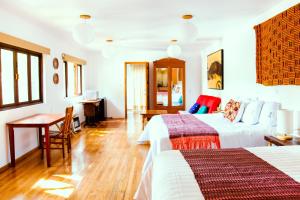 a bedroom with two beds and a table and a desk at Casa Jacinta Guest House in Mexico City