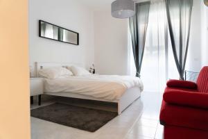 um quarto branco com uma cama e uma cadeira vermelha em Re di Roma bright home em Roma