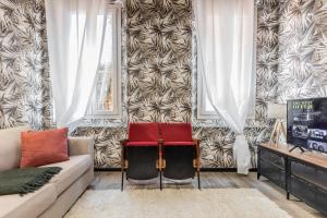 a living room with a couch and two red chairs at Borgonuovo Apartments in Bologna