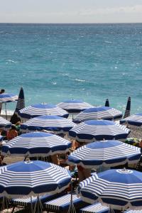 eine Gruppe von blauen und weißen Sonnenschirmen am Strand in der Unterkunft Très bel appartement vue mer à Nice in Nizza