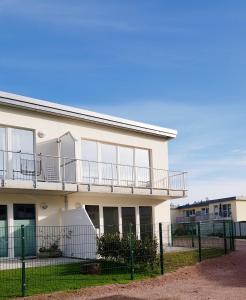 a white building with a balcony and a fence at Fewo Graal Müritz Sobierajczyk in Gelbensande