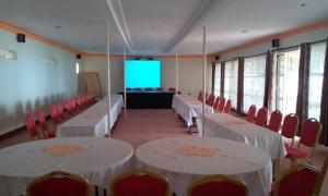 a room with white tables and red chairs and a screen at Mirembe Resort Beach Hotel Ssese in Kalangala