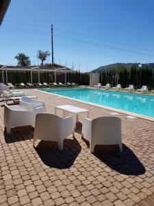 un grupo de mesas y sillas junto a una piscina en Agriturismo Paparanza, en Valguarnera Caropepe