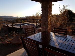 einen Holztisch und Stühle auf einer Terrasse mit Whirlpool in der Unterkunft Lodge Twentyfour Mabalingwe Nature Reserve in Bela-Bela