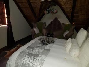 a bedroom with a bed with a white comforter and chairs at Lodge Twentyfour Mabalingwe Nature Reserve in Warmbaths