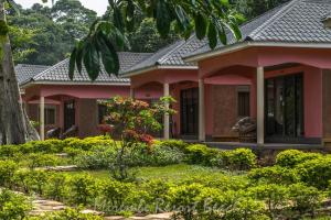 Kalangala的住宿－Mirembe Resort Beach Hotel Ssese，粉红色的房子,前面有一个花园