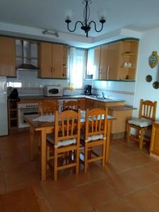 una cocina con armarios de madera, mesa y sillas en Apartamento Paraiso Sol, en Torrox Costa