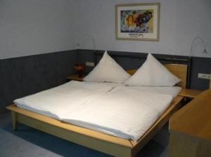 Bett mit weißer Bettwäsche und Kissen in einem Zimmer in der Unterkunft Hotel zur Post Garni in Landkern