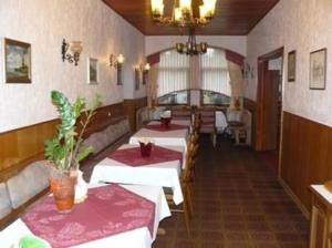 ein Esszimmer mit 2 Tischen und einem Kronleuchter in der Unterkunft Hotel zur Post Garni in Landkern
