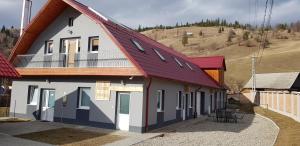 a house with a red roof with a balcony at Antal Guesthouse in Ghimeş-Făget