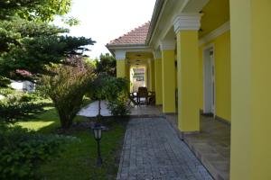 a house with yellow walls and a walkway at Arany Tisza Vendégház in Poroszló