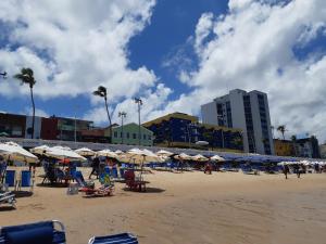 a beach with umbrellas and chairs and people on it at Bahia Flat 301 in Salvador