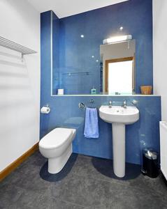 a blue bathroom with a toilet and a sink at The Arches, Borthwick Mains Farm, in Gorebridge