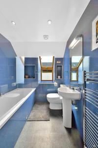 戈爾布里奇的住宿－The Arches, Borthwick Mains Farm,，蓝色的浴室设有水槽、浴缸和卫生间。