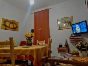 a dining room with a table and a tv at La Casa di Pina in Modica