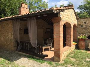 a brick building with a patio with a table and a chair at Agriturismo le Colline in Montescudaio