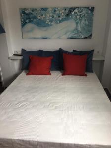 1 cama grande con 2 almohadas rojas. en El Pez Naranja, en Zahara de los Atunes