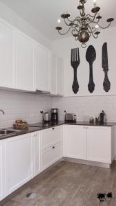 a kitchen with white cabinets and utensils on the wall at República Guest House in Coimbra