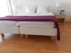 a large white bed with a purple blanket on it at T2 Bassin d'Arcachon, 200m plage, centre-ville in Andernos-les-Bains