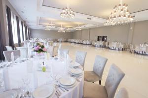 um salão de banquetes com mesas e cadeiras brancas e lustres em Malinowy Dwór Wieluń em Wieluń