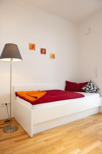 Cama blanca con sábanas rojas y lámpara en MyRoom - Top Munich Serviced Apartments, en Múnich
