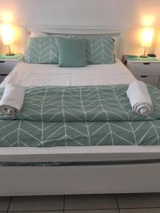 a bed with green and white sheets and pillows at Apartment in Dolphin Heads in Eimeo