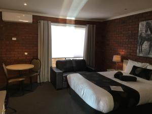 a hotel room with a bed and a couch and a window at Melton Motor Inn and Apartments in Melton