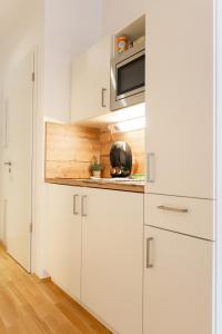 a kitchen with white cabinets and a microwave at MyRoom - Top Munich Serviced Apartments in Munich