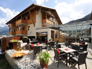een terras met tafels en stoelen voor een gebouw bij Hotel Garni Alpenjuwel in Serfaus