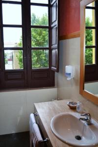 a bathroom with a sink and two windows at Hotel El Carmen in Puente Genil
