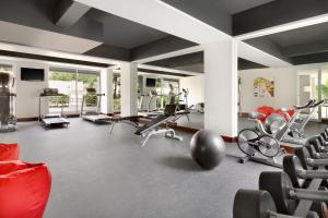 a gym with several treadmills and chairs in a room at Ramada Encore by Wyndham Bali Seminyak in Seminyak