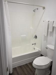 a white bathroom with a toilet and a shower at Palm Inn Motel - Montclair in Montclair +2 photos