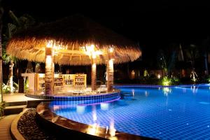 a swimming pool with a straw umbrella and a resort at Phi Phi CoCo Beach Resort in Phi Phi Islands