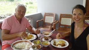 a man and a woman sitting at a table with food at Suman Beach Rooms in Nilaveli