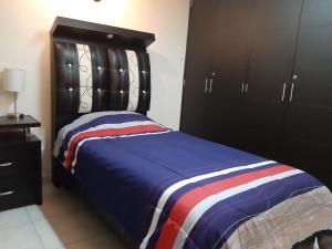 a bedroom with a bed with a striped blanket at Departamento cómodo y completo en Toluca in Toluca