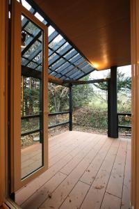 een afgeschermde veranda met een raam en een houten vloer bij ASANOHA in Furano