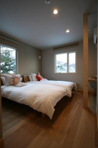 een groot bed in een kamer met 2 ramen bij ASANOHA in Furano