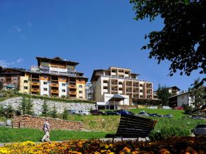 a person walking through a park with a bench and buildings at Hotel Garni Alpenjuwel in Serfaus