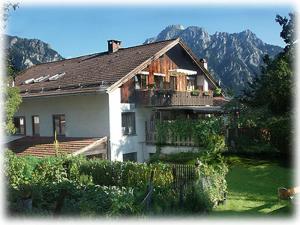 a house with a balcony and mountains in the background at Haus am Weiher in Schwangau