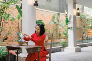 une femme assise à une table avec un vase dans l'établissement IAMSAIGON homestay, à Hô-Chi-Minh-Ville