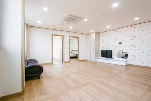 an empty living room with a couch and a television at Jeju Special Pension in Jeju