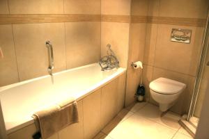 a bathroom with a bath tub and a toilet at Queens Casino and Hotel in Queenstown +8 photos