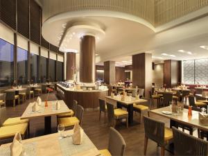 a restaurant with tables and chairs and a bar at Hotel Santika Pandegiling - Surabaya in Surabaya