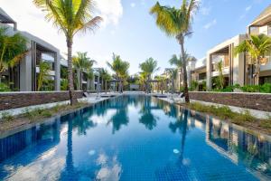 a swimming pool with palm trees in front of buildings at Mont Choisy Le Parc by Pam Golding in Grand-Baie