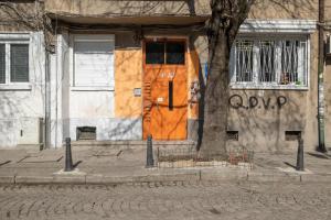 a building with an orange door next to a tree at Feel Sofia - one bedroom apartment next to Russian Square in Sofia
