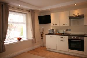 a kitchen with white cabinets and a window at The Thomas Suite in Llandudno