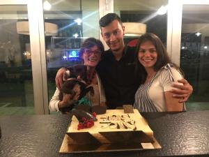 Ein Mann und zwei Frauen stehen vor einem Geburtstagskuchen in der Unterkunft B&B Homer Trento in Trient