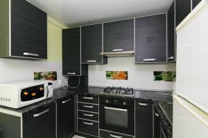 Una cocina con gabinetes negros y un microondas. en 16 вулиця Прокоф'єва, en Sumy 2 fotos más