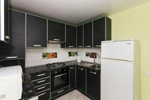 een keuken met zwarte kasten en een witte koelkast bij 16 вулиця Прокоф'єва in Sumy